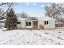 Charming single-story home featuring large picture windows and a well-maintained front yard covered in a layer of fresh snow at 7135 W 24Th Ave, Lakewood, CO 80214