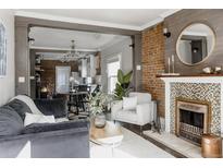 Inviting living room featuring an exposed brick wall, decorative fireplace, and hardwood floors at 1788 S Sherman St, Denver, CO 80210