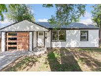 Charming renovated home with a modern wood-paneled garage door and manicured lawn at 2430 Eaton St, Edgewater, CO 80214