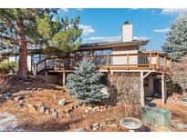 Beautifully landscaped backyard featuring a spacious deck and mature trees offering privacy and shade at 837 Meadow Run, Golden, CO 80403