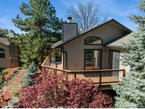Beautiful home featuring a charming deck, lush landscaping, mature trees and architectural details at 837 Meadow Run, Golden, CO 80403