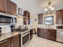 Well-lit kitchen showcasing stainless steel appliances, granite countertops and dark wood cabinets at 424 S Leyden St, Denver, CO 80224