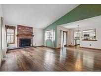 Bright living room with a beautiful fireplace, hardwood floors, and a large window at 2838 S Heather Gardens Way # A, Aurora, CO 80014