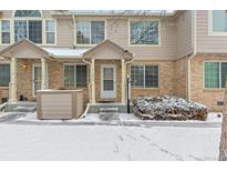 Charming townhome featuring a brick facade and covered entryway during the winter season at 1129 W 112Th Ave # C, Denver, CO 80234