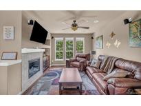 Inviting living room with a fireplace, large windows, and a comfortable leather sofa at 1000 Elmhurst Dr # B, Highlands Ranch, CO 80129