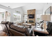 Inviting living room features a stone fireplace, vaulted ceilings, and abundant natural light at 13228 E Asbury Dr, Aurora, CO 80014