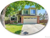 Charming two-story home with lush green lawn, mature trees, and two-car garage at 1052 Northampton Ct, Highlands Ranch, CO 80126