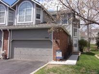 Charming townhouse featuring a two-car garage, brick accents, and well-maintained landscaping at 7707 S Monaco Cir, Centennial, CO 80112