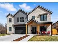 Inviting two-story home boasts a stone and gray exterior, attached two car garage, and covered front porch at 428 Pontiac St, Denver, CO 80220