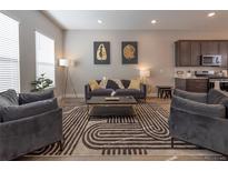 Well-lit living room featuring a comfortable seating arrangement and an open flow to the kitchen at 10177 E 62Nd Ave, Denver, CO 80238