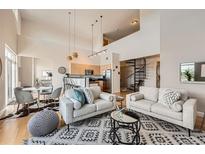 Bright, open-concept living room featuring modern decor and a spiral staircase leading to the second floor at 5677 S Park Pl # D310, Greenwood Village, CO 80111