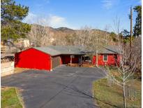 Charming single-Gathering home featuring a bright red exterior, attached garage, and a spacious driveway nestled in a scenic mountain setting at 96 Greeley Blvd, Palmer Lake, CO 80133