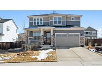 Two-story home with stone accents, gray siding, covered porch, and attached two-car garage at 12264 Olive Way, Thornton, CO 80602