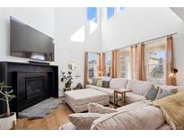 Bright living room featuring a fireplace, large sectional sofa, and lots of natural light at 12264 Olive Way, Thornton, CO 80602