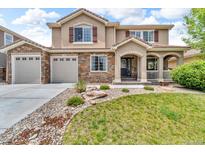 Charming two-story home featuring a stone facade, arched entry, three-car garage and well-manicured lawn at 1385 Candleglow St, Castle Rock, CO 80109