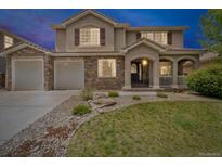Charming two-story home featuring a stone facade and a well-manicured front yard and three-car garage at 1385 Candleglow St, Castle Rock, CO 80109