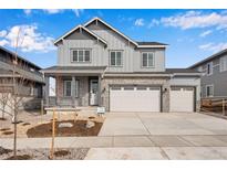 Charming two-story home with a three car garage, covered porch, stone accents, and landscaped front yard at 24661 E 33Rd Dr, Aurora, CO 80019