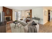 Bright living room featuring a cozy fireplace, plush rug, and comfortable seating with balcony access at 1200 N Emerson St # 205, Denver, CO 80218