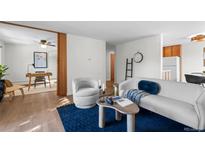 Bright living room showcasing hardwood floors, a white couch, decorative throw pillows, and an adjacent room with a writing desk at 1200 N Emerson St # 205, Denver, CO 80218