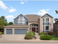 Charming two-story home featuring a three car garage and a brick archway leading to the main entrance at 8425 Green Island Cir, Lone Tree, CO 80124