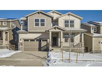 Two-story house with gray siding, a large garage, and snowy landscaping at 5581 Wisteria Ave, Firestone, CO 80504