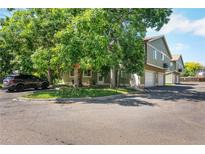 A view of the townhouse, with mature trees, and a car parked in front at 1155 S Fairplay Cir # D, Aurora, CO 80012