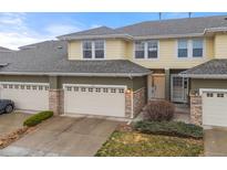 Inviting exterior view of a two-story townhome with a two-car garage and stone accents at 3000 E 112Th Ave # 102, Northglenn, CO 80233