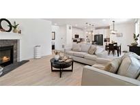 Open-concept living area featuring a fireplace, a comfortable sofa, and seamless flow to the kitchen and dining area at 1369 E Witherspoon Dr, Elizabeth, CO 80107
