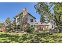 Charming home with a stone chimney and lush landscaping, set against a clear blue sky at 6145 S Perry Park Rd, Sedalia, CO 80135