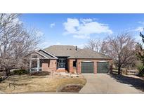 Charming red brick home featuring an attached two-car garage and a well-maintained front yard at 283 Huntley Ct, Castle Pines, CO 80108
