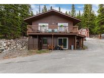 Charming two-story cabin with a large deck surrounded by lush greenery and a red barn at 159 Lake Rd, Idaho Springs, CO 80452