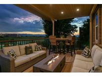 Inviting covered deck featuring comfortable seating, a fire table, and scenic mountain views at twilight at 10258 Pennington Ln, Highlands Ranch, CO 80126