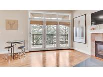 Bright living room with hardwood floors, fireplace, and access to balcony with serene views at 2700 E Cherry Creek South Dr # 220, Denver, CO 80209