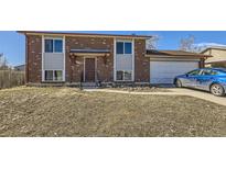 Charming two-story brick home featuring an attached garage and a well-maintained lawn at 10932 W 107Th Ave, Broomfield, CO 80021