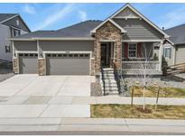 Charming home featuring a stone facade, two-car garage and cozy porch, perfect for relaxed suburban living at 10987 Ouray St, Commerce City, CO 80022