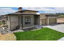 Beautiful home with a modern design, stone accents, and a well-manicured lawn at 6196 Oxford Peak Ln, Castle Rock, CO 80108