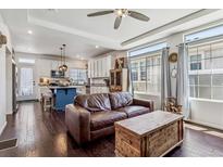 Inviting living room with a cozy leather sofa, hardwood floors, and an open-concept kitchen, perfect for modern living at 10560 Waco St, Commerce City, CO 80022