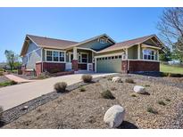 Charming green home featuring a well-manicured front yard and a red brick facade with a two-car garage at 23312 E Chestnut Pl, Aurora, CO 80016
