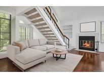 Bright living room features hardwood floors, fireplace, modern staircase, and neutral decor at 4802 E Kentucky Ave # E, Denver, CO 80246