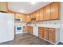Bright kitchen featuring wooden cabinets, white appliances, and modern tile backsplash at 775 S Alton Way # 3C, Denver, CO 80247