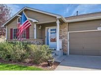 Charming home with a tidy front yard, American flag, and inviting brick accents at 11462 Iola St, Commerce City, CO 80640