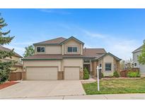 Charming two-story home with three-car garage and manicured front yard landscaping on a sunny day at 9983 Cottoncreek Dr, Highlands Ranch, CO 80130