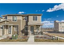 Charming two-story townhome with covered porch and landscaped front yard, complemented by a blue sky at 12301 Festival Ln, Thornton, CO 80241