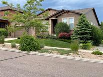 Charming brown home featuring a well-manicured lawn and beautiful landscaping at 15789 W 95Th Pl, Arvada, CO 80007