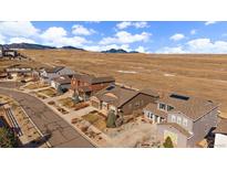 A suburban neighborhood with varied architecture sits at the base of scenic foothills under a partly cloudy sky at 15789 W 95Th Pl, Arvada, CO 80007