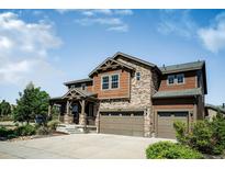 Beautiful two-story home featuring a stone facade, three-car garage, and a covered front porch at 9607 Williamsburg St, Littleton, CO 80125