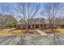 Stately two-story brick home with a tile roof and a basketball court visible in the front yard at 2 Foxtail Cir, Cherry Hills Village, CO 80113