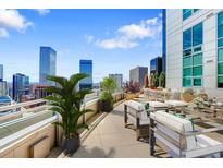 Wide shot of balcony with outdoor seating and views of the Denver skyline on a sunny day at 2001 Lincoln St # 2524, Denver, CO 80202