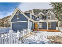 Charming two-story home with a gray exterior, white picket fence, and mountain views at 1438 Marion St, Georgetown, CO 80444