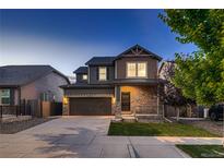 Charming two-story home featuring stone accents, a covered porch, a two-car garage, and manicured landscaping at 15595 E 47Th Dr, Denver, CO 80239